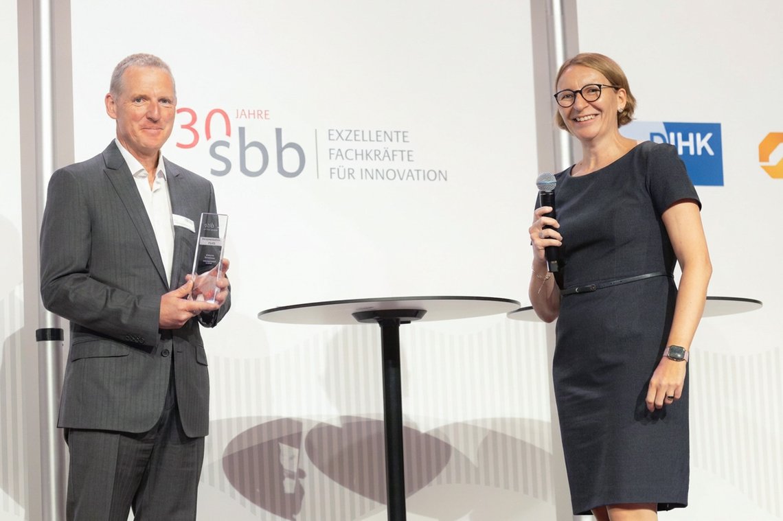 Herr Grabenauer steht mit dem Preis in der Hand auf der Bühne neben Melanie Lochner.