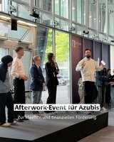 Geförderte Azubis stehen auf einem Podest im IHK Gebäude, neben ihnen steht der Moderator.