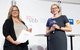 Carolin Weiler und Melanie Lochner stehen gemeinsam auf der Bühne. Frau Weiler steht links und hält den Preis und eine Urkunde in der Hand.