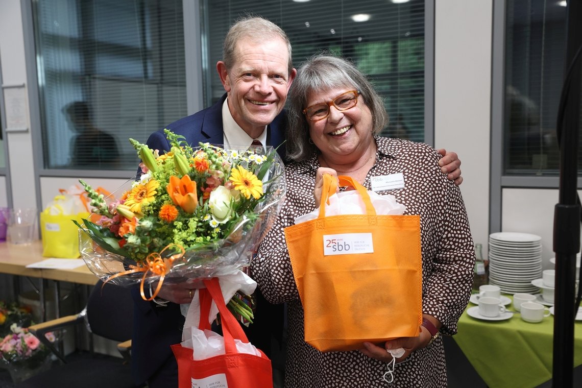 Geschäftsführer und Stellvertreterin des Geschäftsführers der SBB stehen nebeneinander mit Blumenstrauß in der Hand